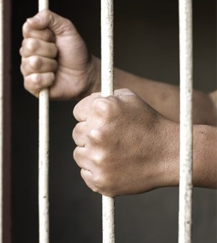 two hands gripping jail bars